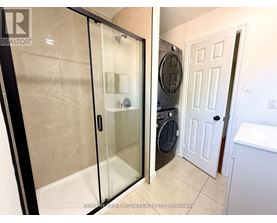 A bathroom with a glass shower door and a white door.