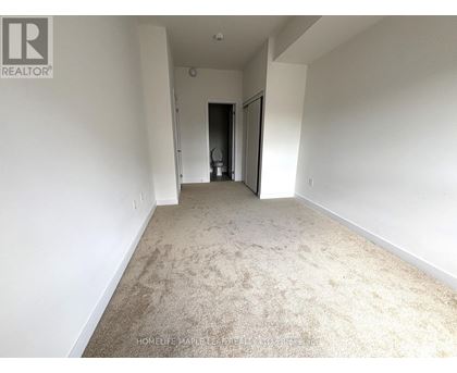A spacious room with a carpeted floor and white walls.