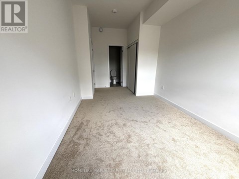A spacious room with a carpeted floor and white walls.