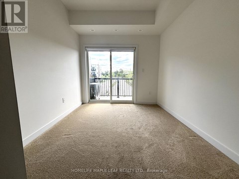 A room with a carpeted floor and a sliding glass door leading to a balcony.