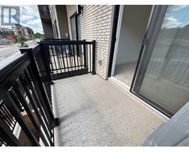 A balcony with a black railing and a glass door leading to a room.