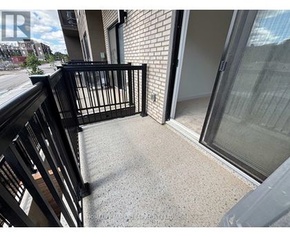 A balcony with a black railing and a glass door leading to a room.