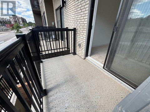 A balcony with a black railing and a glass door leading to a room.