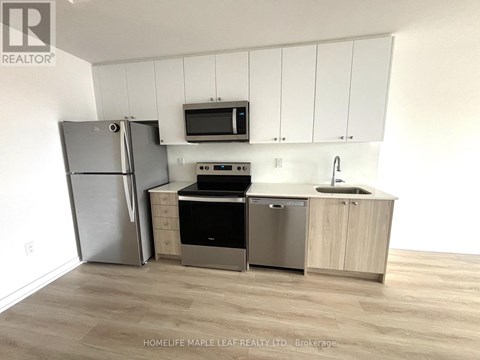 A kitchen with a refrigerator, microwave, oven, sink and cabinets.