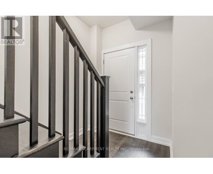 A hallway with a white door and a wooden staircase.