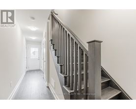 A staircase with a wooden handrail and steps leading up to a door at the end of the hallway.