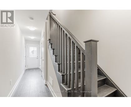 A staircase with a wooden handrail and steps leading up to a door at the end of the hallway.