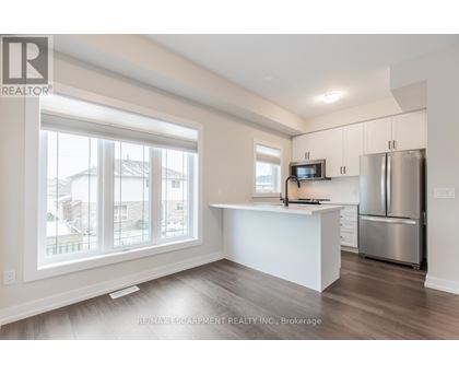 A spacious kitchen with white cabinets and a stainless steel refrigerator.