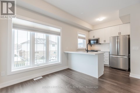 A spacious kitchen with white cabinets and a stainless steel refrigerator.