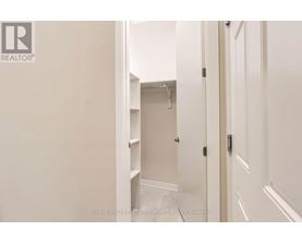 A white hallway with a door on the right and a closet with shelves on the left.