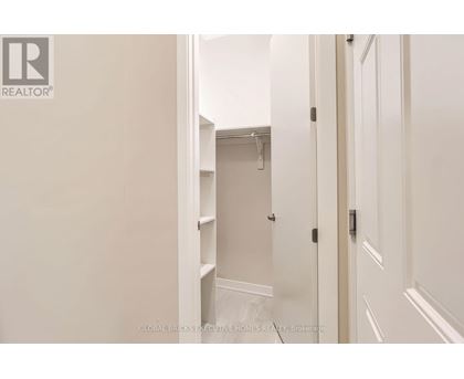 A white hallway with a door on the right and a closet with shelves on the left.