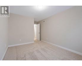 A spacious room with beige carpeting and white walls.