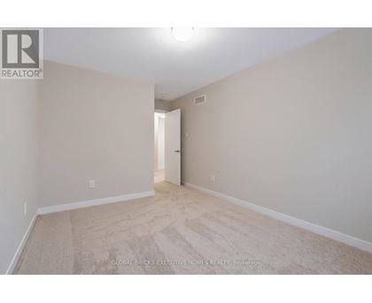 A spacious room with beige carpeting and white walls.