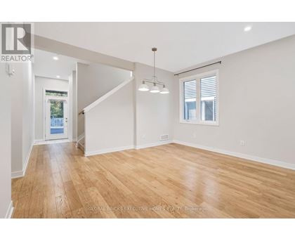 A spacious room with wooden flooring and white walls.