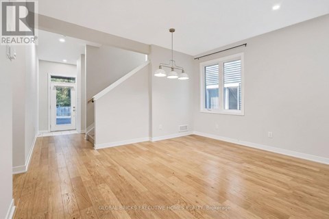 A spacious room with wooden flooring and white walls.