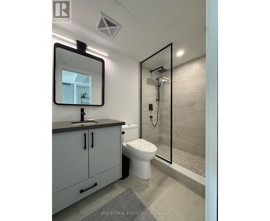 A bathroom with a toilet, sink, and mirror.