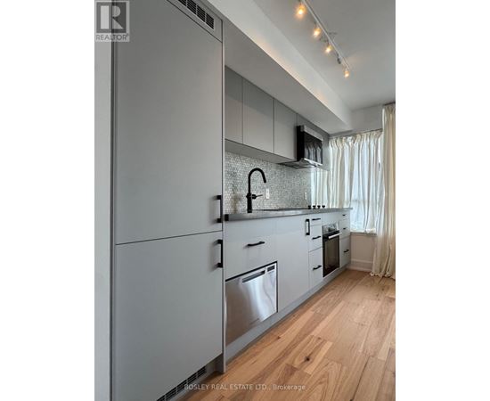 A modern kitchen with wooden floors and stainless steel appliances.