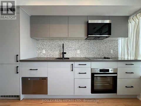 A modern kitchen with white cabinets and a black countertop.