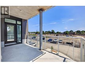 A balcony with a view of a parking lot and buildings.