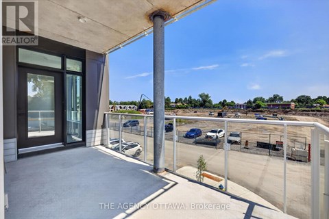 A balcony with a view of a parking lot and buildings.