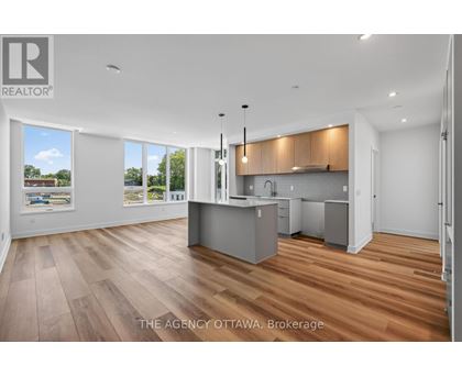 A well-lit, spacious kitchen and living room with wooden flooring and large windows.