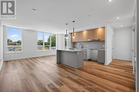 A well-lit, spacious kitchen and living room with wooden flooring and large windows.