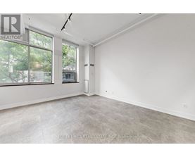 A spacious, empty room with a large window and a door leading to another room.