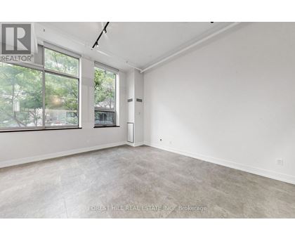 A spacious, empty room with a large window and a door leading to another room.