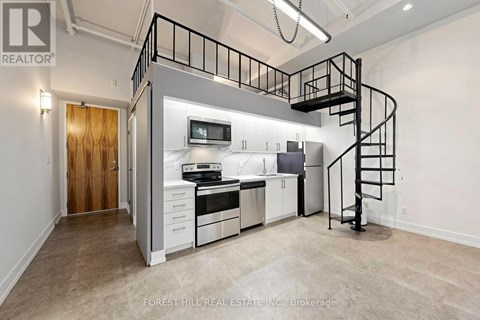 A spacious kitchen with a staircase leading to the upper level.