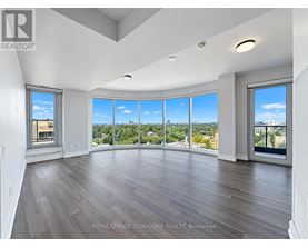 A spacious room with wooden floors and large windows overlooking a cityscape.