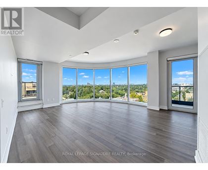 A spacious room with wooden floors and large windows overlooking a cityscape.