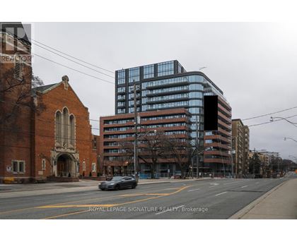 A car is driving down a street past a church and a large building.