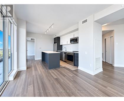 A modern kitchen with dark wood floors and white walls.