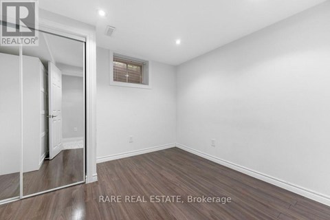 A room with a wooden floor and white walls, with a door on the left side.