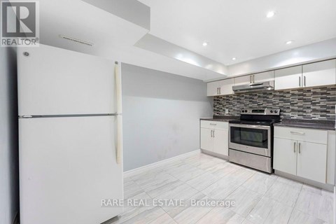 A kitchen with white cabinets and a stone backsplash.