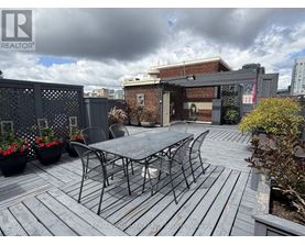 A patio with a table and chairs is set up on a wooden deck.