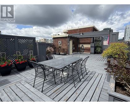 A patio with a table and chairs is set up on a wooden deck.