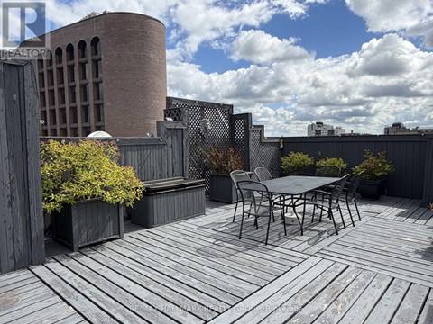 A wooden deck with a table and chairs in the foreground and a building in the background.