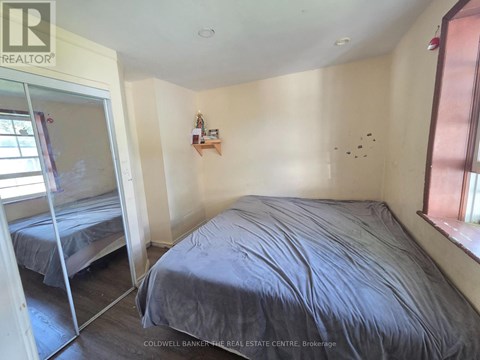 A bedroom with a bed, a window, and a shelf with items on it.