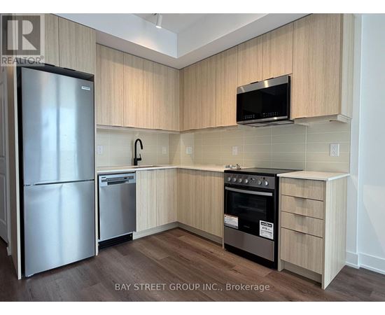 A kitchen with a refrigerator, oven, and microwave.