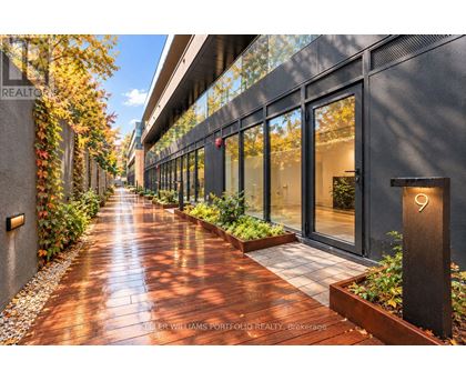 A long, narrow walkway with a metal railing on the left and a glass door on the right.