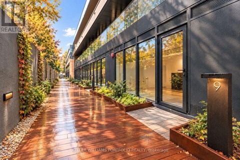 A long, narrow walkway with a metal railing on the left and a glass door on the right.