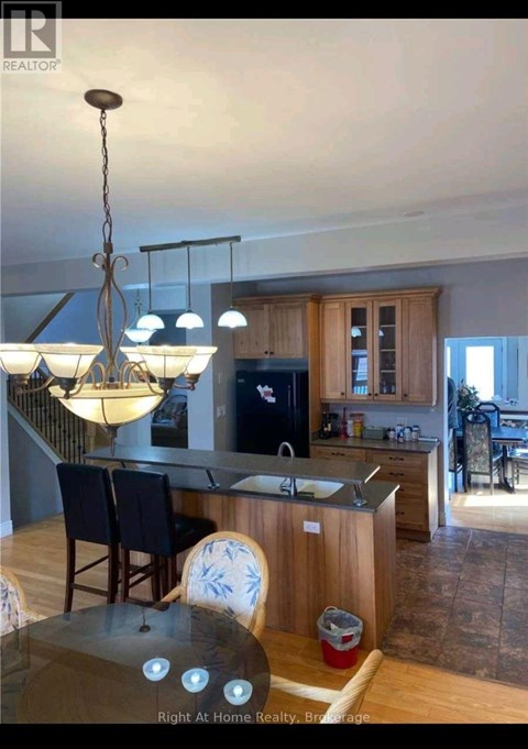 A kitchen with a table and chairs in the foreground and a dining area in the background.