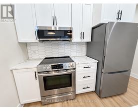 A modern kitchen with white cabinets and stainless steel appliances.