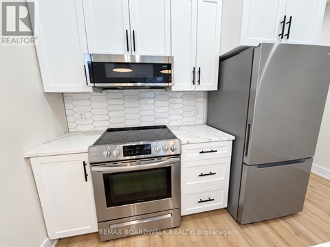 A modern kitchen with white cabinets and stainless steel appliances.