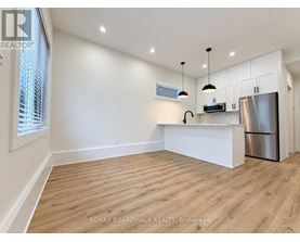 A kitchen with white cabinets and a wooden floor.