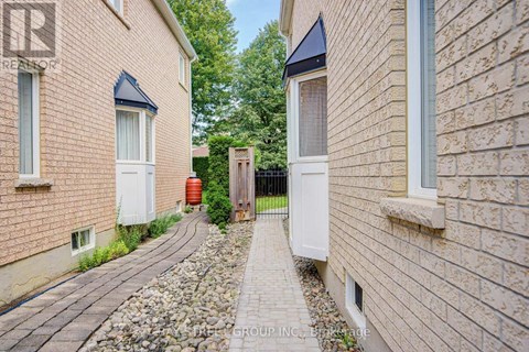 A narrow pathway between two brick buildings with a white door on the right.