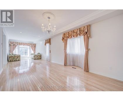 A spacious room with wooden floors and a chandelier.