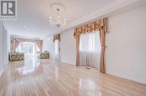A spacious room with wooden floors and a chandelier.