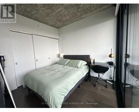 A bedroom with a bed, chair, and a window.